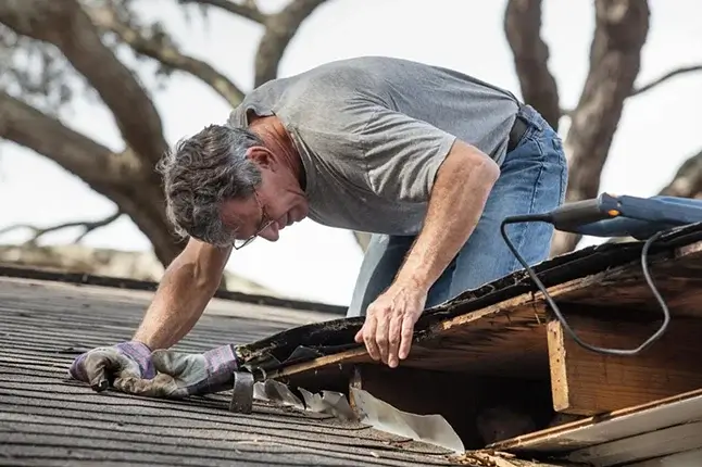 A man repairing a broken roof.