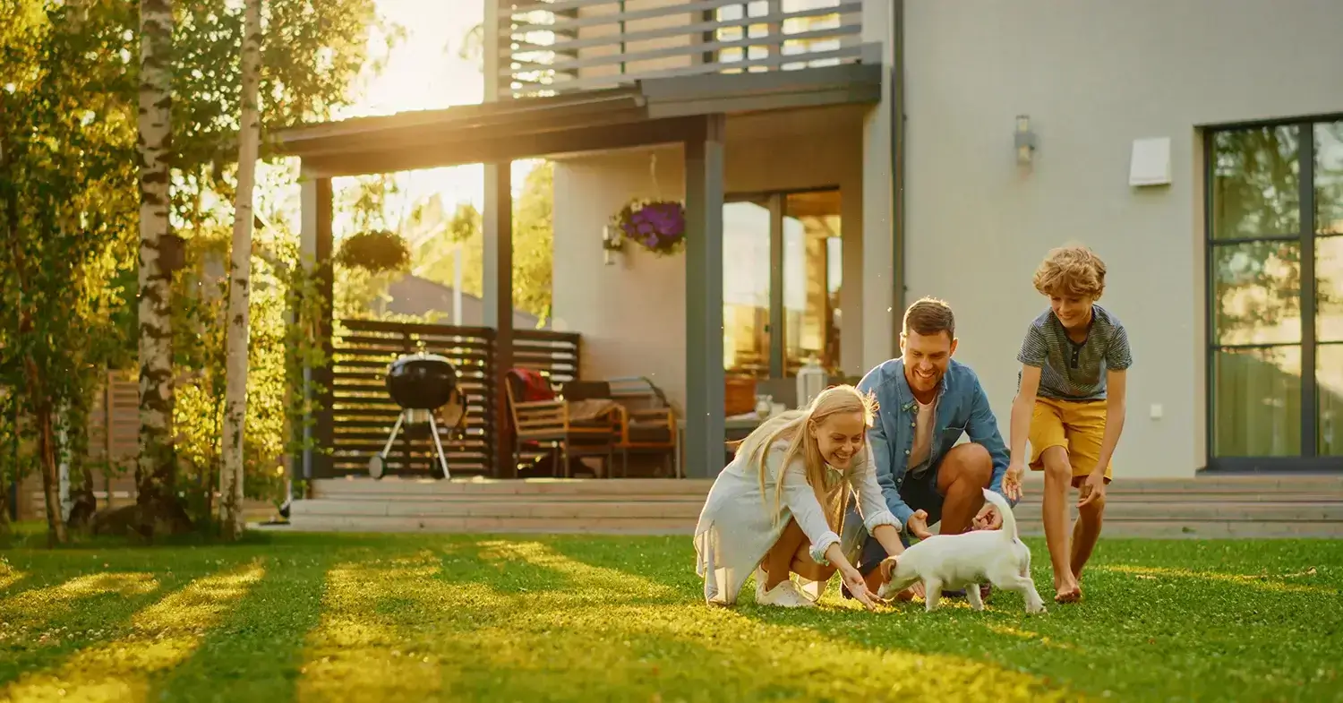 A couple playing with a puppy in front of their home.