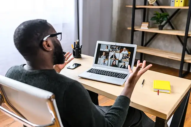 A man talking with expressive hands in a virtual meeting on a laptop